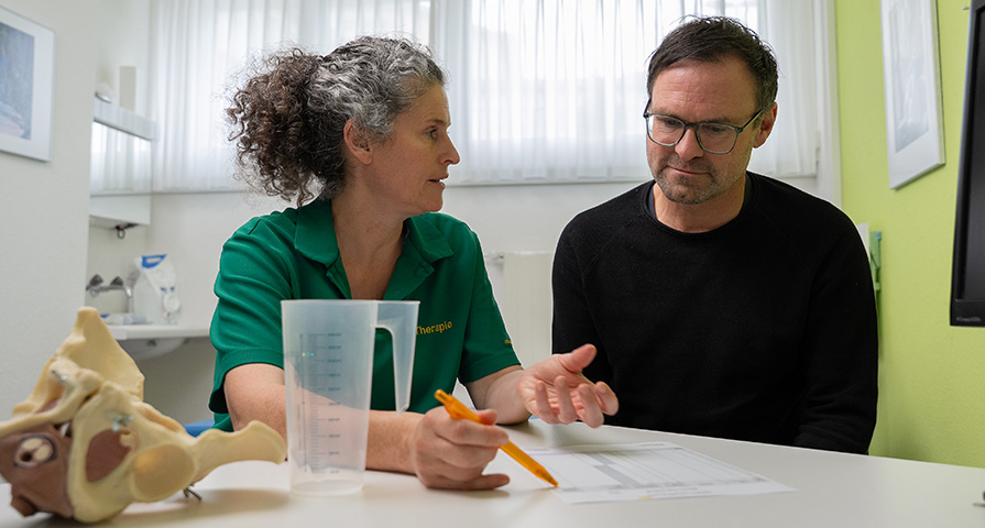 Beckenboden-Rehabilitation bei den Spitälern Schaffhausen Eine Beckenboden-Physiotherapeutinnen erklärt einem Patienten die Anatomie und Funktion des Beckenbodens